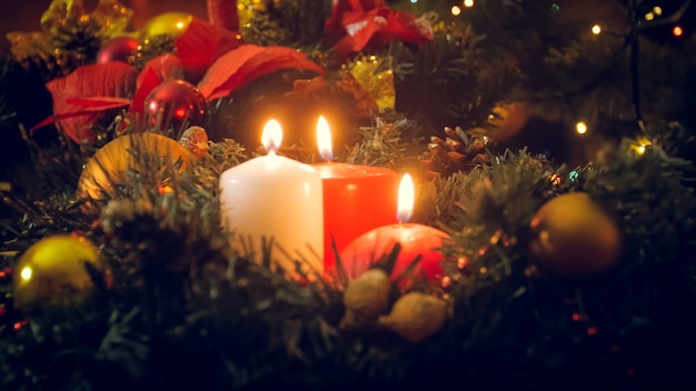 Fond de vacances d'hiver. Bougies de Noël brûlant sur une couronne de l'Avent à côté de coffrets cadeaux colorés