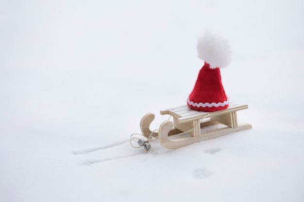 Fond de vacances d'hiver : chapeau de père Noël sur un traîneau en bois. Fermer