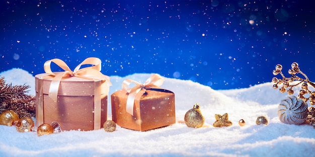 Fond de vacances d'hiver avec des coffrets cadeaux écologiques et des ornements de Noël dorés sur la neige