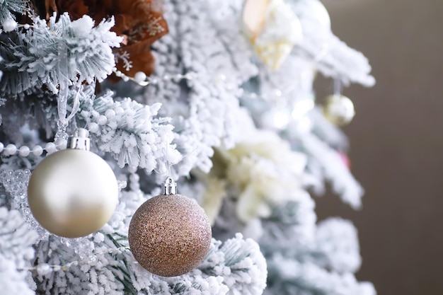 Fond de vacances de Noël. Boule d'argent et de couleur suspendue à un arbre décoré avec bokeh et neige, espace de copie.