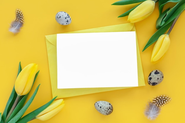 Fond de vacances de Pâques avec des oeufs de caille de carte de voeux et des fleurs de tulipes jaunes sur fond jaune Carte de voeux plate avec un espace pour le texte Décoration de Pâques Modèle de conception de Pâques