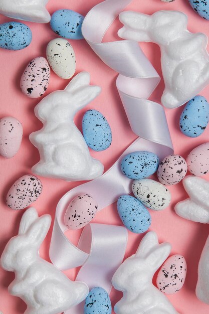 Fond de vacances de Pâques rose pastel avec des oeufs et des lapins de Pâques