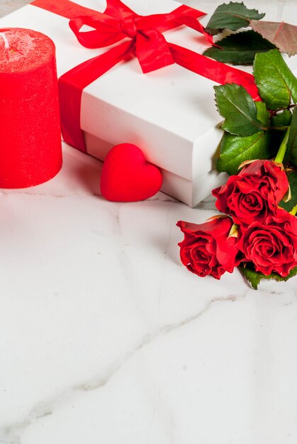 Fond de vacances, Saint Valentin. Bouquet de roses rouges, cravate avec un ruban rouge, avec coffret cadeau enveloppé. Sur table en marbre blanc