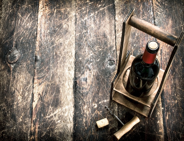 Fond de vin Une bouteille de vin rouge sur un support avec un tire-bouchon sur un fond en bois