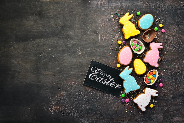 Fond de voeux de Pâques Biscuits de pain d'épice de Pâques et oeufs colorés décoratifs Sur fond marron Vue de dessus espace de copie gratuit