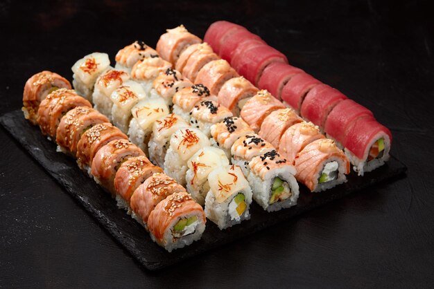 Fond de vue de dessus avec ensemble de différents types de rouleaux de sushi colorés placés sur fond noir