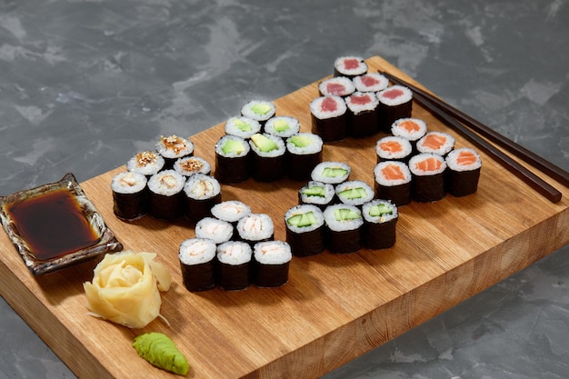 Fond de vue de dessus avec ensemble de différents types de rouleaux de sushi colorés placés sur une planche de bois