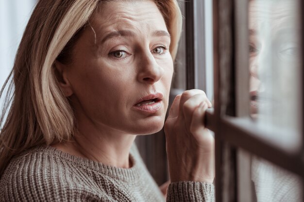 Fondre en larmes. Femme mature déprimée aux cheveux blonds se sentant stressée fondant en larmes