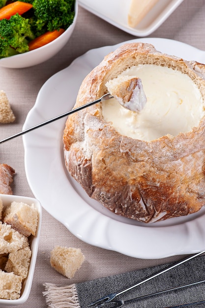 Fondue au fromage crémeuse à l'intérieur du pain italien. Fourchette tremper le pain dans le fromage à la crème