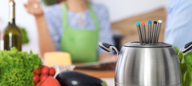 Fondue dans une casserole à l'arrière-plan d'amis cuisinant ensemble gros plan Intérieurs de cuisine et ustensiles de cuisine