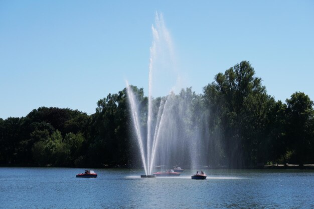 Photo une fontaine dans le lac contre un ciel bleu clair