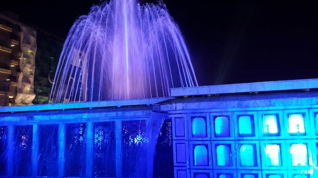 Photo une fontaine éclairée la nuit.