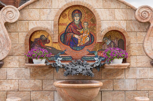 Fontaine avec fleurs et image mosaïque de la Vierge Marie avec Jésus-Christ