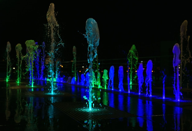 Fontaine de nuit illuminée, jets d'eau multicolores dans le noir