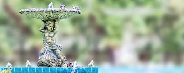 Fontaine avec une sculpture pour enfants de garçon dans un jardin avec espace de copie gratuit