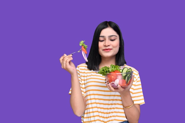 foodie girl holding cuillère et bol de salade et le regardant modèle pakistanais indien