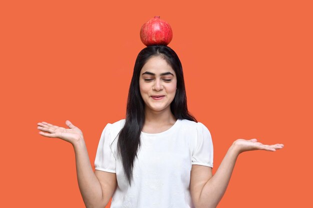 foodie girl wearing white t-shirt équilibrant une pomme sur sa tête modèle pakistanais indien