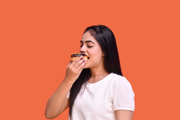 foodie girl wearing white t-shirt et manger du chocolat dount indain modèle pakistanais