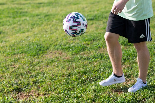 Football acrobatique. Le jeune homme s'entraîne avec un ballon de football. Joueur s'entraînant aux figures de base avec le ballon.