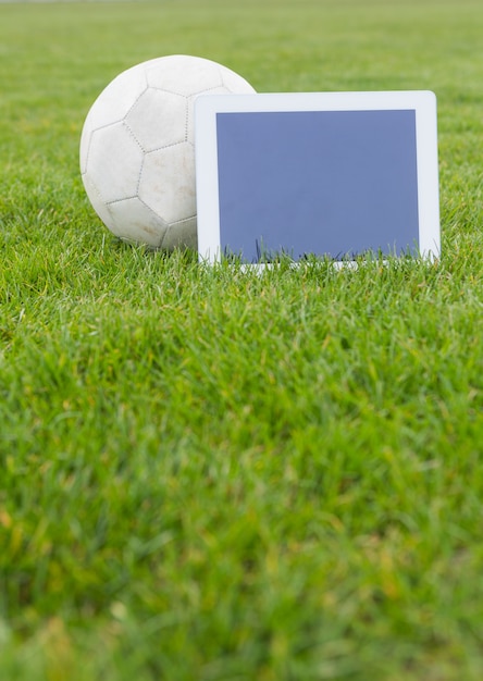 Football et tablette avec écran blanc sur le terrain