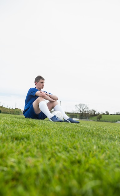 Footballeur en bleu faisant une pause sur le terrain