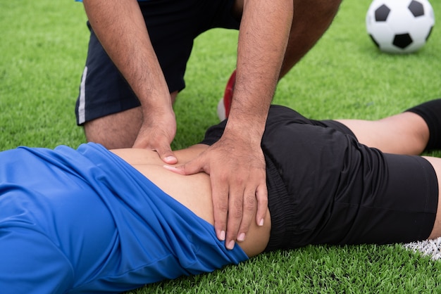 Footballeur vêtu d&#39;une chemise bleue, un pantalon noir blessé dans la pelouse pendant la course.