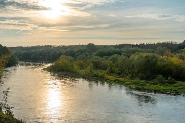 Forêt d'automne le long de la rivière et du lac Le soleil couchant illumine la cime des arbres Rive sablonneuse escarpée au-dessus d'une large rivière Promenades d'automne dans des endroits écologiquement propres