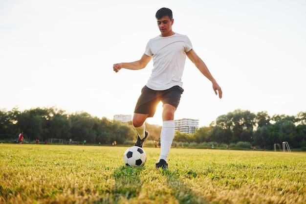 Forêt sur fond Jeune footballeur s'entraîne sur le terrain sportif