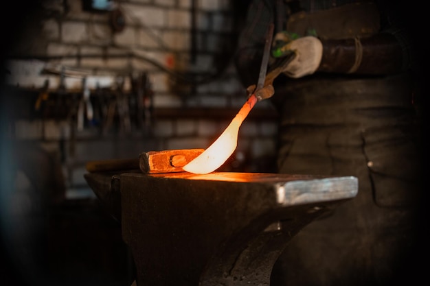 Forger un couteau à partir du métal chaud en tenant le couteau entre les pinces