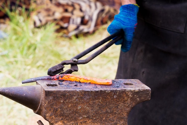 Le forgeron fixe un fer chaud sur l'enclume pour forger