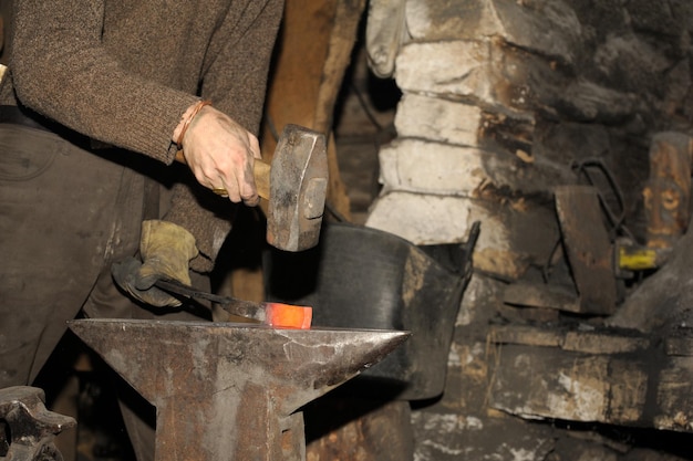 Le forgeron travaillant dans la forge traite le métal La photographie sur le thème de la forge