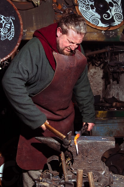 Photo le forgeron viking forge des armes dans l'ancienne forge vintage.