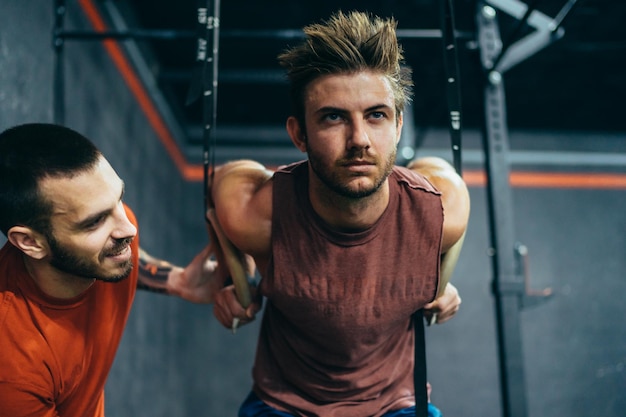 Photo formateur aidant un homme à faire des exercices avec un trx