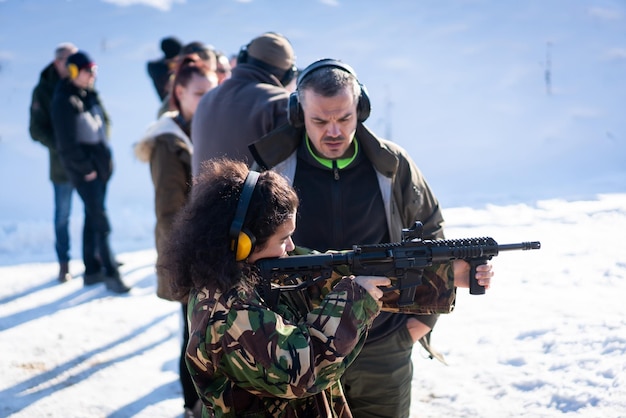 Formateur aidant une jeune femme à viser avec une arme de poing lors d'un entraînement au combat. Photo de haute qualité