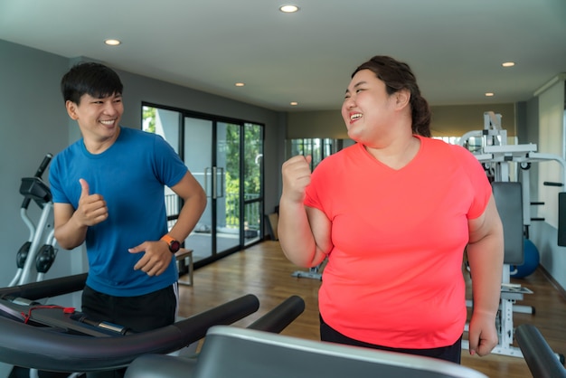 Formateur asiatique homme et femme en surpoids exerçant la formation sur tapis roulant dans la salle de gym