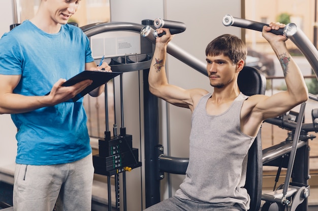 Formateur contrôle l&#39;exercice physique de l&#39;homme