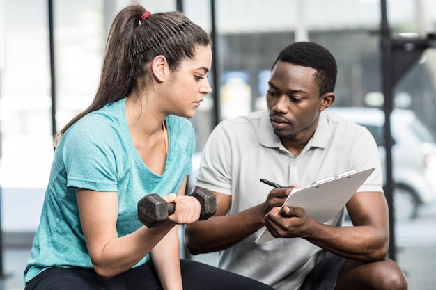 Photo formateur donnant des conseils à une femme au gymnase