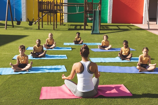 Formateur enseignant le yoga aux élèves dans la cour de l'école