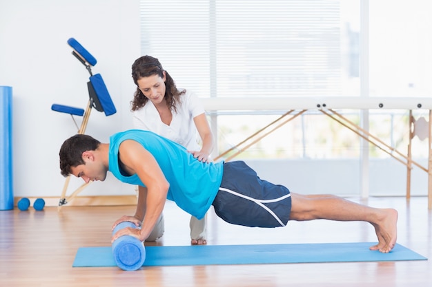 Formateur travaillant avec l&#39;homme sur un tapis d&#39;exercice