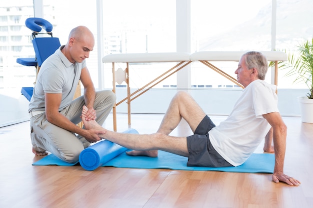 Formateur travaillant avec l&#39;homme sur un tapis d&#39;exercice