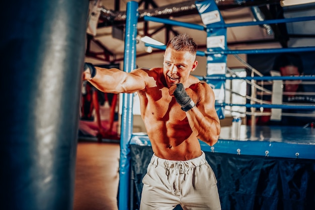 Formation de boxeur sur un sac de boxe dans la salle de sport