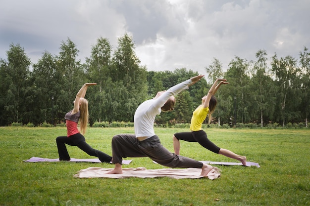 Formation dans le parc - l'instructeur montre un exercice de flexibilité pour un groupe de filles dans le parc, tôt le matin