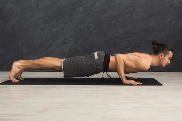 Formation d'entraînement de planche d'homme de forme physique au fond blanc à l'intérieur. Le jeune homme fait de l'exercice. Mode de vie sain, concept de gymnastique