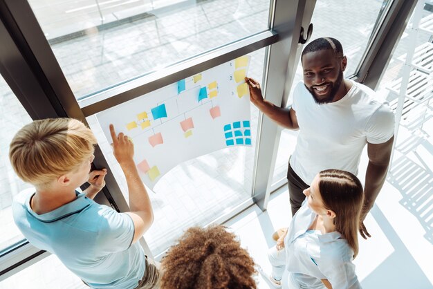 Formation en groupe. De jeunes collègues professionnels gais debout au bureau et travaillant sur le projet tout en profitant du travail de groupe