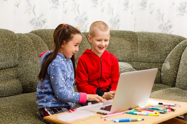 Formation en ligne à distance. écolier et fille étudiant à la maison avec un ordinateur portable et faisant leurs devoirs. Assis à une table
