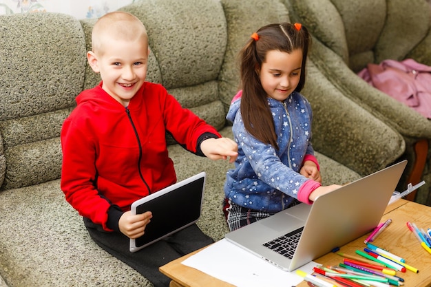 Formation en ligne à distance. écolier et fille étudiant à la maison avec un ordinateur portable et faisant leurs devoirs. Assis à une table