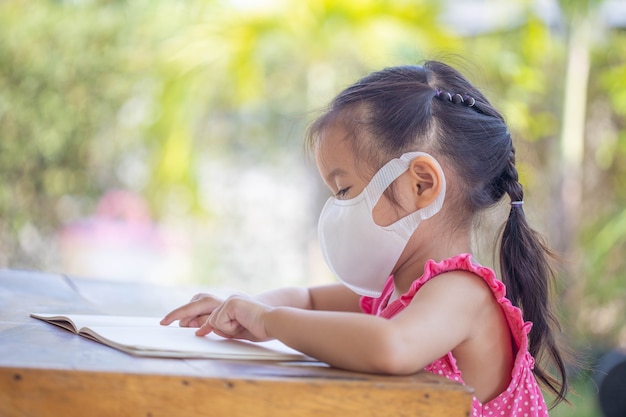 Formation en ligne à distance. enfant dans un masque pour regarder une leçon en ligne.