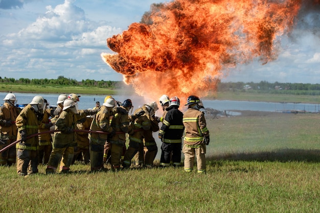 Formation des pompiers et des sauveteurs Pompiers pulvérisant de l'eau à haute pression sur le feu Arrière-plan de la flamme du feu brûlant