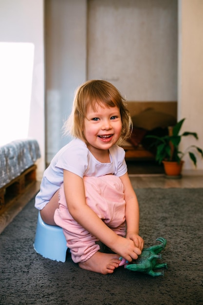 Formation de pot mignon fille bambin jouant avec ses jouets sur le pot