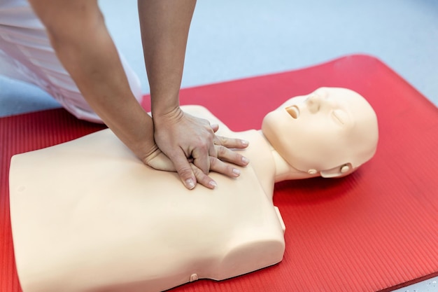 Formation en réanimation cardiopulmonaire procédure médicale Démonstration de compressions thoraciques sur une poupée de réanimation cardiaque dans la classe Formation en premiers soins Réanimation cardiopolmonaire Cours de premiers soins sur un mannequin de réactivation cardiaque